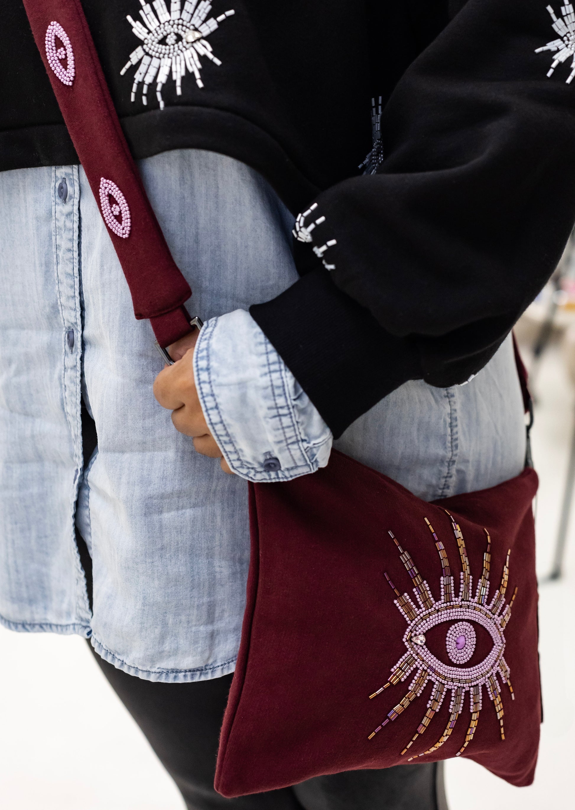 Woman wearing a sustainably and ethically handcrafted burgundy purse dress with a beaded eye pattern.