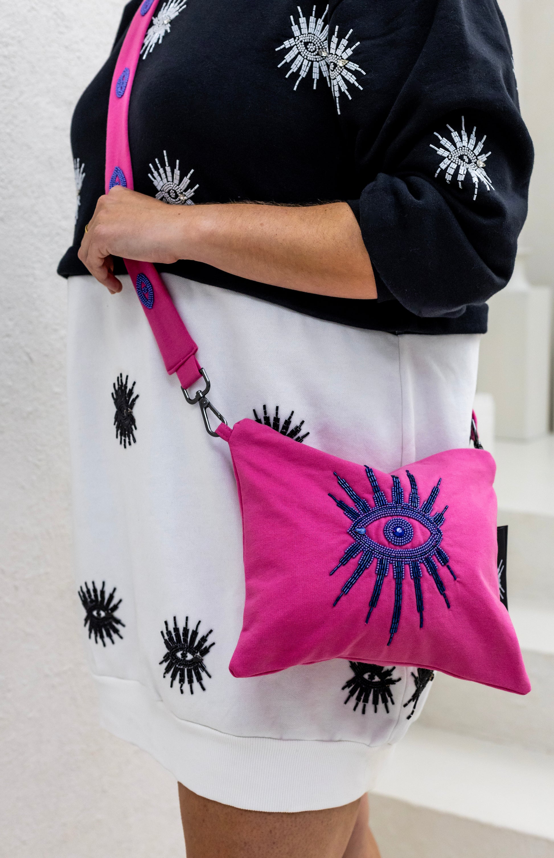 Woman wearing a sustainably and ethically handcrafted pink purse dress with a beaded eye pattern.