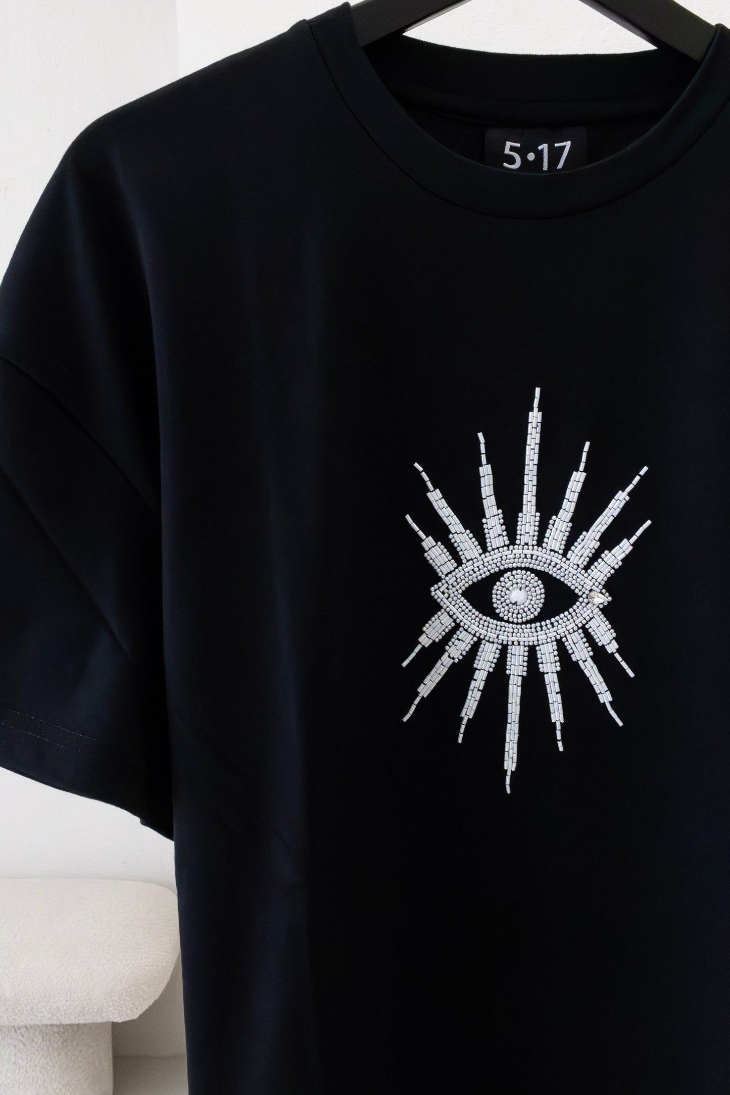 Sustainably and ethically handcrafted black shirt with a white beaded eye.