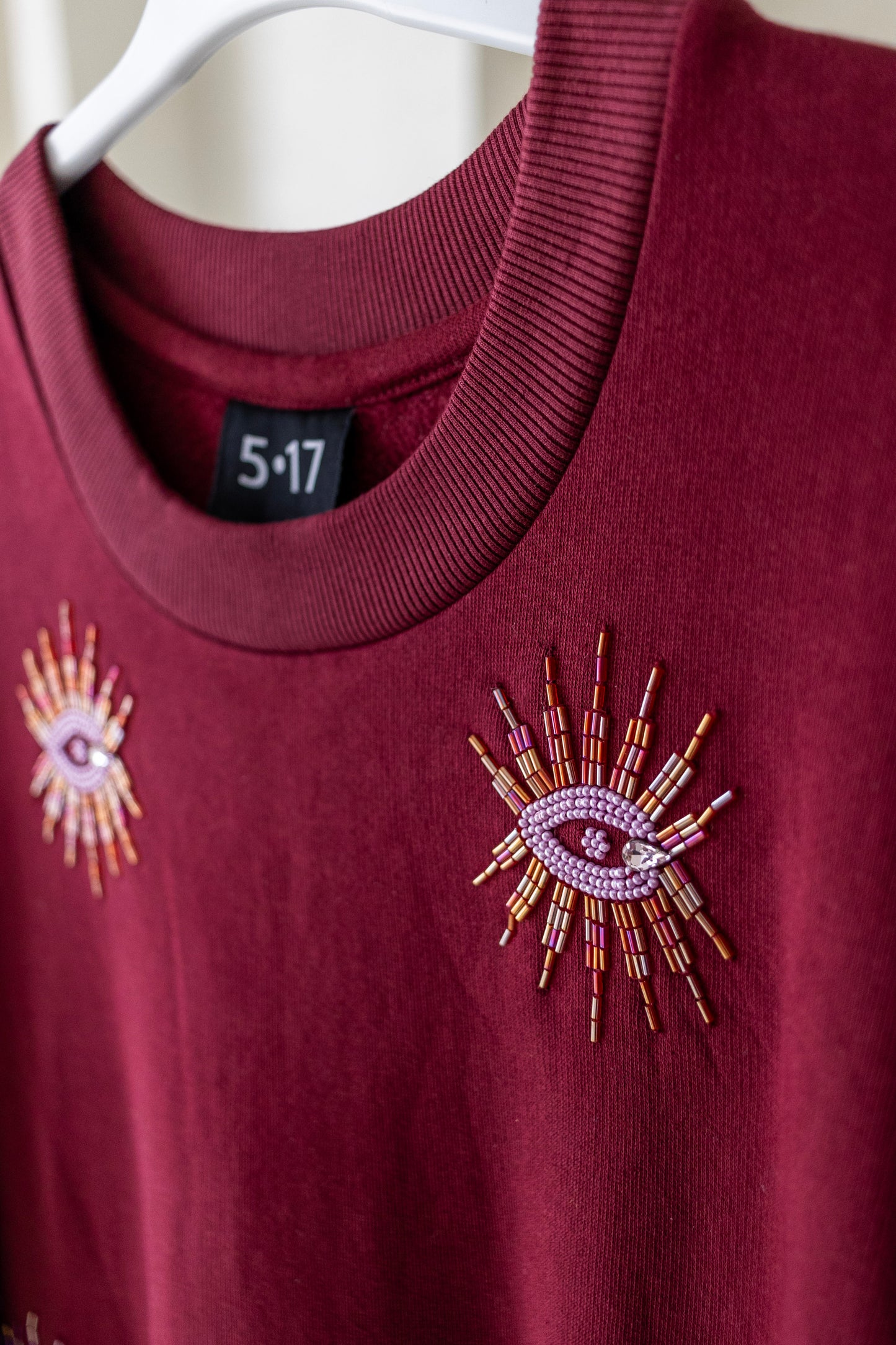 Sustainably and ethically handcrafted burgundy sweatshirt dress with a beaded eye pattern.