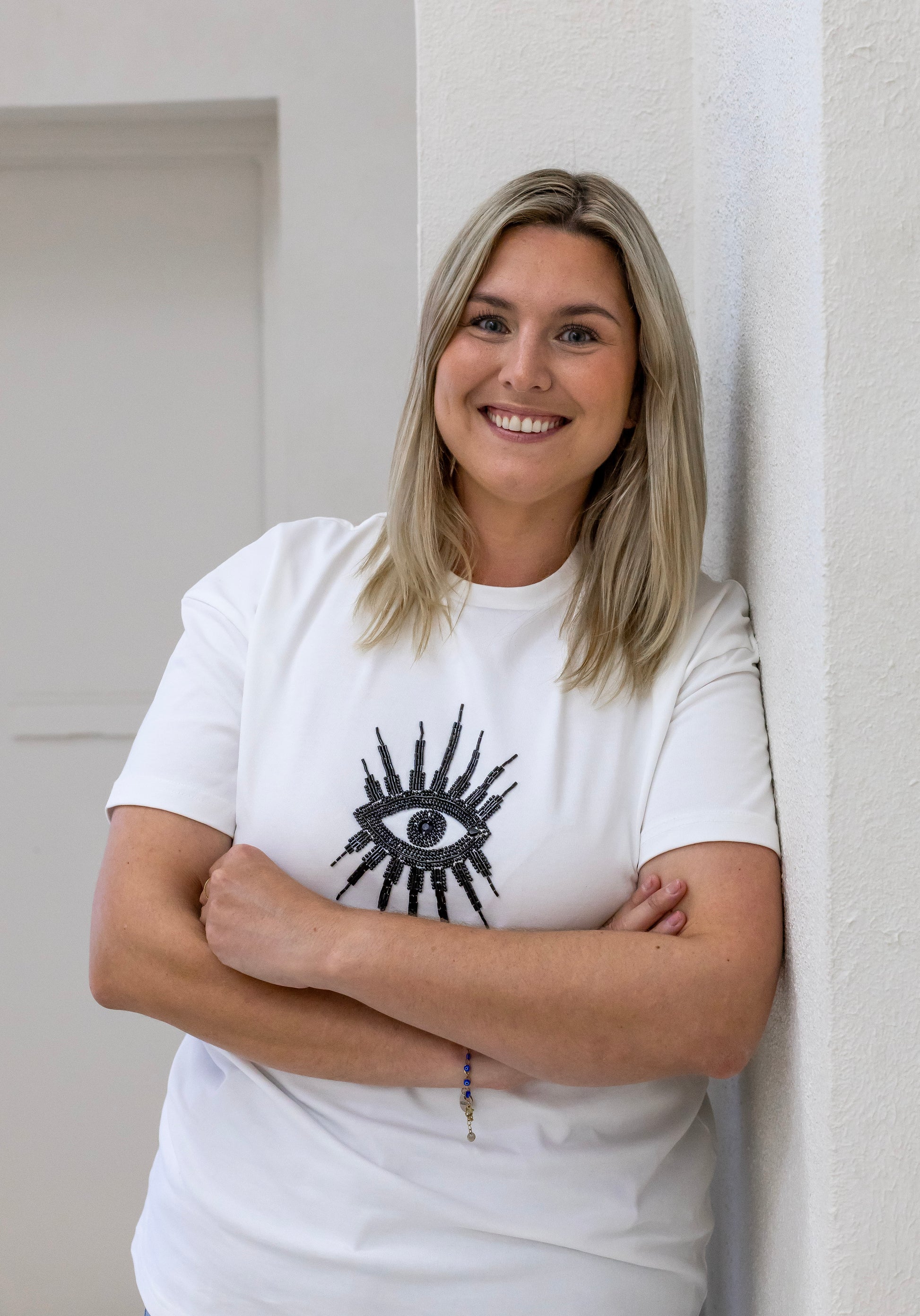 Woman wearing a sustainably and ethically handcrafted white t-shirt with a black beaded eye pattern.