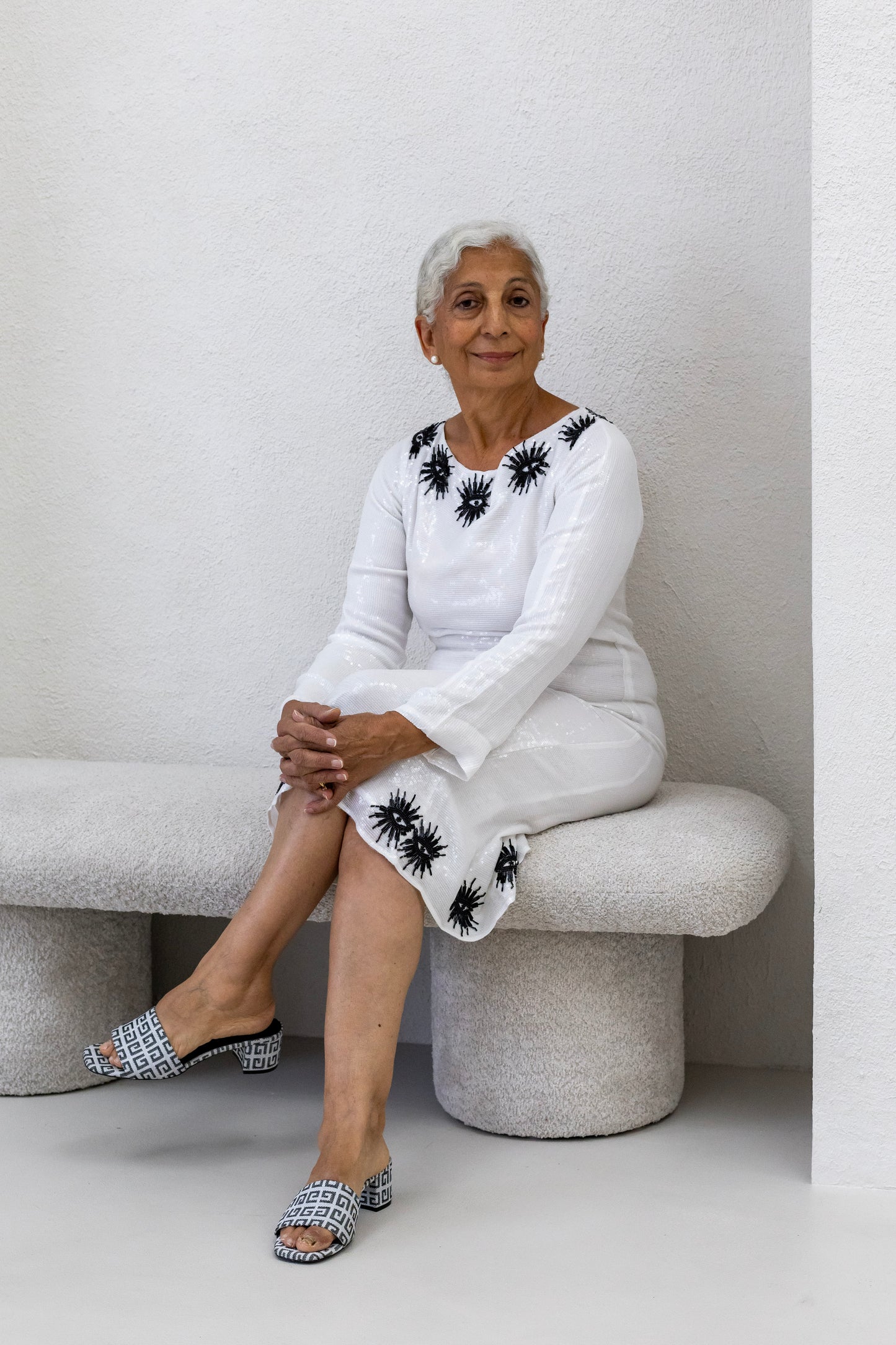 Woman wearing a sustainably and ethically handcrafted white sequin dress with a black eye pattern.