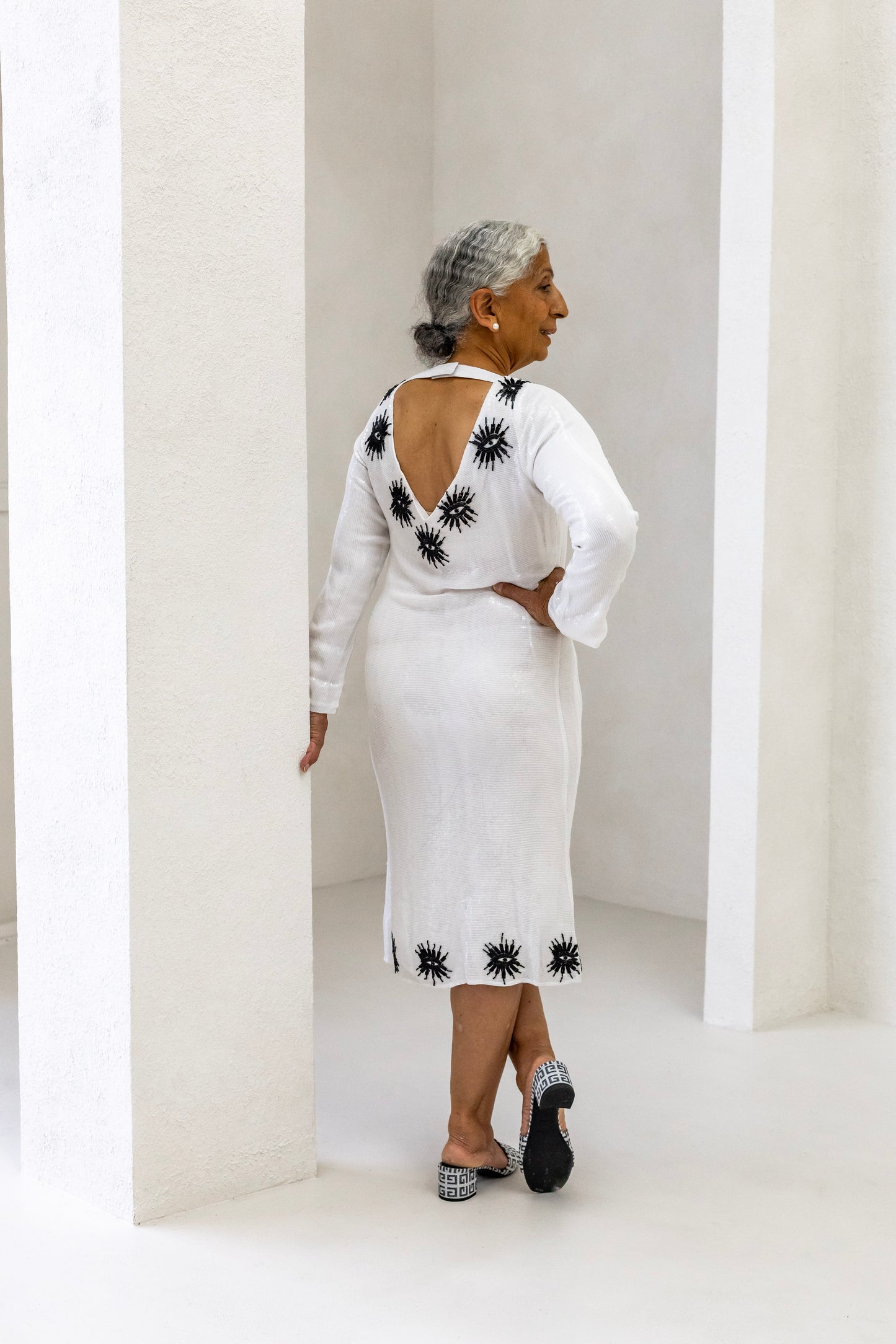 Woman wearing a sustainably and ethically handcrafted white sequin dress with a black eye pattern.