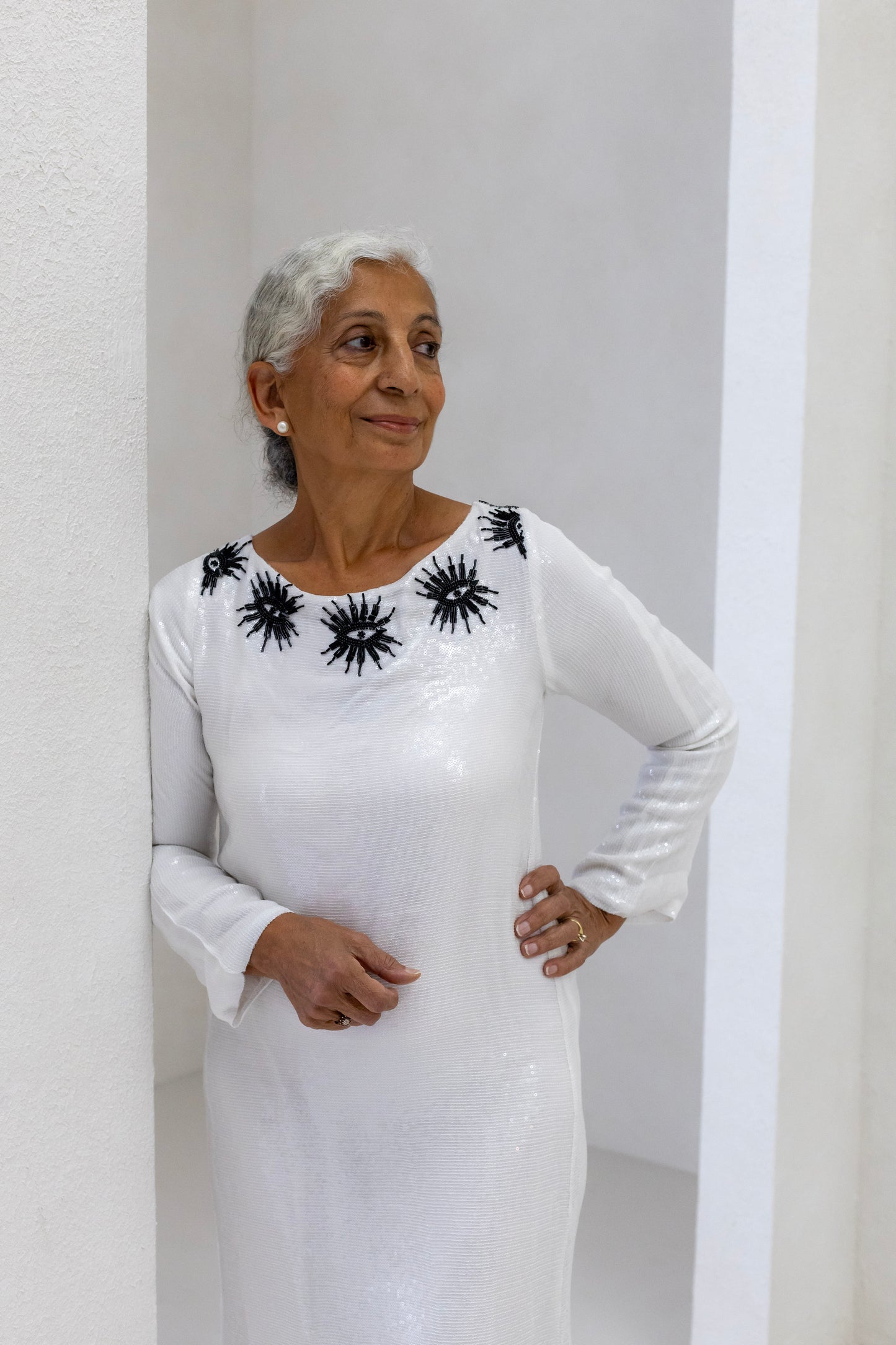 Woman wearing a sustainably and ethically handcrafted white sequin dress with a black eye pattern.