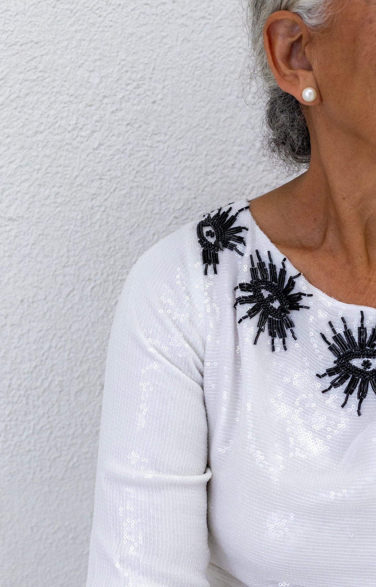 Woman wearing a sustainably and ethically handcrafted white sequin dress with a black eye pattern.