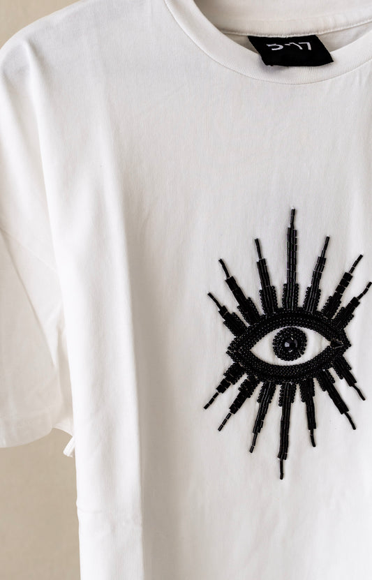 Sustainably and ethically handcrafted white shirt with a black beaded eye.